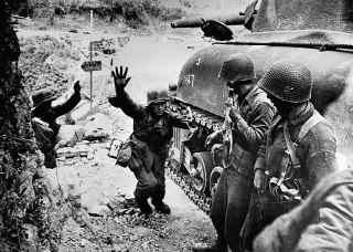 这张照片拍摄于1944年意大利战场,记录了德国士兵向盟军投降的场景。1944年是意大利战役的关键时期。盟军在1943年登陆意大利后,与德军在亚平宁半岛展开了艰苦的战斗。到1944年,随着盟军攻势加强,越来越多的德国士兵选择投降。