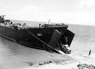 美国海军登陆舰 LST-207，由美国海岸警卫队人员操作，于1943年11月26日停靠在所罗门群岛瓜达尔卡纳尔岛的库库姆海滩。LST（Landing Ship, Tank）是一种用于运输坦克、车辆和士兵直接登陆作战海滩的船只。这次行动是在瓜达尔卡纳尔战役期间，美军为了夺取和巩固战略岛屿而进行的重要登陆行动的一部分。